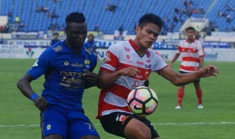 Pesepak bola Persib Bandung Ezechiel Ndouasel (kiri) berebut bola dengan pesepak bola Madura United FC Fachrudin Wahyudi Aryanto (kanan) pada laga lanjutan GO-JEK Traveloka Liga 1 di Stadion Si Jalak Harupat Soreang, Kabupaten Bandung, Jawa Barat, Kamis (19/10). 