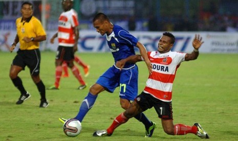 Pesepak bola Persib Bandung, Ferdinand Sinaga (kiri) berebut bola dengan pesepak bola Persepam Madura United, Issac Djober (kanan) dalam pertandingan Piala Gubernur Jawa Timur 2013 di Stadion Gelora Bangkalan, Madura, Jatim, Ahad (15/12).