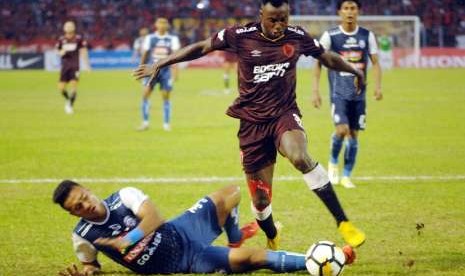 Pesepak bola PSM Makassar Nke Ondoua Guy Junior (kanan) berebut bola dengan pesepak bola Arema FC M Rafli (kiri) dalam lanjutan Liga 1 di Stadion Andi Mattalatta, Makassar, Sulawesi Selatan, Minggu (14/10). Tuan rumah PSM Makassar menang melawan Arema FC dengan skor 2-1 (1-0)