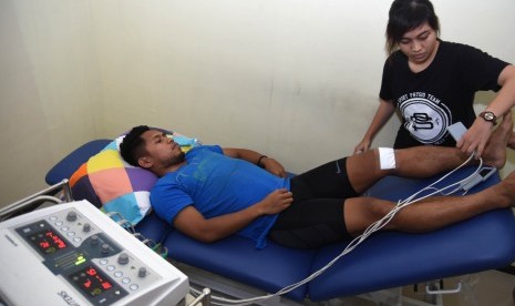 Pesepak bola tim nasional Indonesia Andik Vermansyah (kiri) menjalani terapi penyembuhan cedera di Physiopreneur Sport Physiotherapy kawasan Surabaya Barat, Jawa Timur, Senin (16/1). 