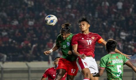 Pesepak bola Timnas Indonesia Fachrudin W Aryanto tengah) dan pesepak bola Bangladesh Bishwanath Ghosh (kiri) berebut bola di udara saat laga persahabatan FIFA di Stadion Si Jalak Harupat, Kabupaten Bandung, Jawa Barat, Rabu (1/6/2022).