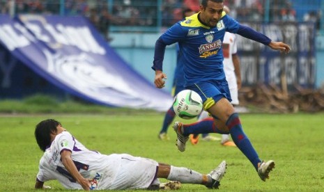 Pesepakbola Arema Indonesia Cronous, Gustavo Lopez (atas) melompat untuk menghindari hadangan pesepakbola Persik Kediri, Tamsil (bawah) dalam pertandingan Piala Gubernur Grup B di Stadion Kanjuruhan, Malang, Jawa Timur, Jumat (20/12). Arema menjadi juara g