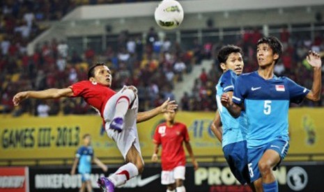 Pesepakbola Indonesia Hendra Adi Bayauw (kiri) berebut bola dengan pesepakbola Singapura Ali Hudzaifi (kanan) dalam pertandingan babak kualifikasi grup E Piala Asia (AFC) U-22 di Stadion Utama Riau, Pekanbaru, Riau, Ahad (15/7)  