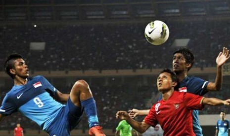 Pesepakbola Indonesia Hendra Adi Bayauw (tengah) berebut bola dengan pesepakbola Singapura Safirul bin Sulaiman (kiri) dalam pertandingan babak kualifikasi grup E Piala Asia (AFC) U-22 di Stadion Utama Riau, Pekanbaru, Riau, Ahad (15/7). 