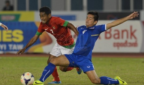   Pesepakbola Indonesia Ramdani Lestaluhu (kiri) berjibaku dengan pemain Thailand pada final sepakbola Sea Games Myanmar 2013 di Stadiun Zheyar Thiri, Naypyitaw, Sabtu (21/12).  (Republika/Edwin Dwi Putranto)