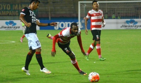 Pesepakbola Madura United, Engelberd Sani (tengah) berebut bola dengan pesepakbola Bali United I Nyoman Sukarja (kiri) dalam pertandingan Torabika Soccer Championship (TSC) di Stadion Delta Sidoarjo, Jawa Timur, Senin (20/6). 