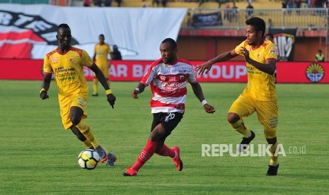 Pesepakbola Madura United (MU) Zah Rahan (tengah) berusaha melewati pesepak bola Sriwijaya FC Konate Makan (kiri) dan Zulfiandi (kiri) dalam kompetisi Go-Jek Liga 1 di Stadion Gelora Ratu Pamelingan (SGRP) Pamekasan, Jawa Timur, Sabtu (7/4).