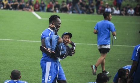 Pesepakbola Persib, Michael Essien menggendong seorang anak sebelum mengikuti latihan rutin di Lapangan Lodaya, Bandung, Jawa Barat, Jumat (31/3). Essien berstatus marquee player pada Liga 1 Indonesia.