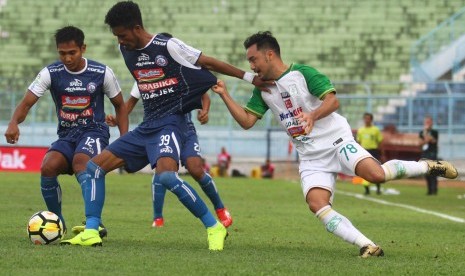 Pesepakbola PSMS Medan, Shohei Matsunaga (kanan) berusaha merebut bola dari pesepakbola Arema FC, Alfin Tuasalamony (tengah), dalam pertandingan Liga I GOJEK di Stadion Kanjuruhan Malang, Ahad (28/10/2018).