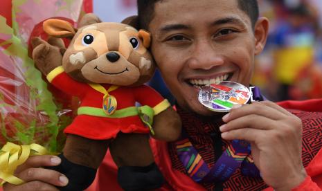 Pesepeda Aiman Cahyadi menggigit medalinya usai pengalungan medali nomor individual time trial road cycling putra SEA Games Vietnam 2021 di Hoa Binh, Vietnam, Jumat (20/5/2022). Aiman meraih medali perak dalam perlombaan tersebut dengan catatan waktu 48 menit 37,903 detik. 