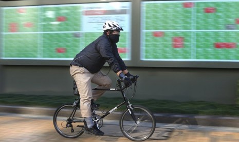 Pesepeda melintas di depan papan indeks sebuah perusahaan sekuritas di Tokyo, Selasa (3/12). Aktivitas pabrik di Jepang memperpanjang masa perlambatannya pada November. Penyebabnya, output dan pesanan baru yang turun sehingga ekonomi Jepang mengalami kontraksi.