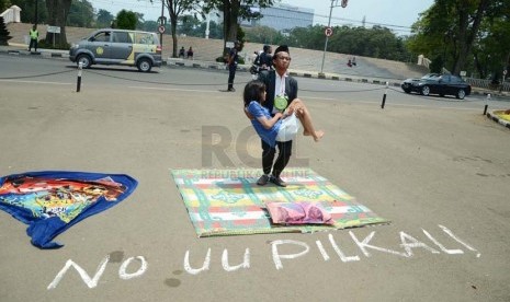  Peserta aksi dari Komunitas Gerbong Bawah Tanah melakukan teaterikal menggambarkan pejabat yang menidurkan hak politik rakyat pada aksi menolak UU Pilkada, di depan Gedung Sate, Kota Bandung, Rabu (1/10).(Republika/Edi Yusuf).