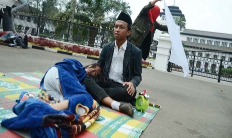  Peserta aksi dari Komunitas Gerbong Bawah Tanah melakukan teaterikal menggambarkan pejabat yang menidurkan hak politik rakyat pada aksi menolak UU Pilkada, di depan Gedung Sate, Kota Bandung, Rabu (1/10).(Republika/Edi Yusuf ).