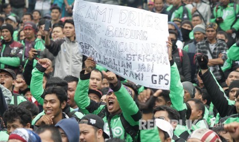 Peserta aksi membawa berbagai poster dan spanduk pada aksi ribuan pengemudi transportasi berbasis aplikasi online di depan Gedung Sate, Kota Bandung, Senin (16/10).