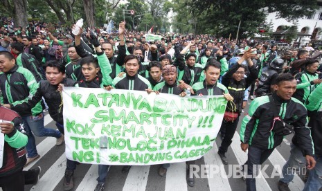 Peserta aksi membawa berbagai poster dan spanduk pada aksi ribuan pengemudi transportasi berbasis aplikasi online di depan Gedung Sate, Kota Bandung, Senin (16/10).