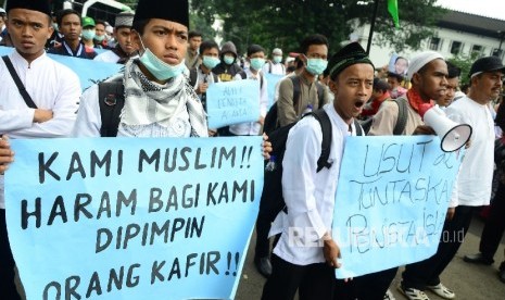  Peserta aksi membentangkan poster di depan Gedung Sate, Kota Bandung, pada Aksi demonstrasi umat Islam terkait pernyataan kontoversi Gubernur DKI Jakarta, Basuki Tjahaja Purnama atau Ahok yang mengutip salah satu ayat Alquran, Jumat (21/10). 