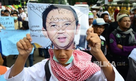 Peserta aksi membentangkan poster di depan Gedung Sate, Kota Bandung, pada aksi demonstrasi umat Islam terkait pernyataan kontoversi Gubernur DKI Jakarta, Basuki Tjahaja Purnama atau Ahok yang mengutip salah satu ayat Alquran, Jumat (21/10).