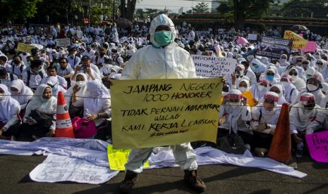 Peserta aksi yang tergabung dalam Forum Komunikasi Honorer Fasilitas Pelayanan Kesehatan (fasyankes) Jawa Barat berunjuk rasa di depan Gedung Sate, Bandung, Jawa Barat. Dalam aksinya, tenaga kesehatan honorer tersebut menuntut untuk non-ASN nakes dan non-nakes yang bekerja di fasyankes pemerintah baik di puskesmas maupun rumah sakit untuk segera diakomodir dan diangkat sebagai ASN maupun PPPK menyesuaikan PP nomor 49 tahun 2018. 