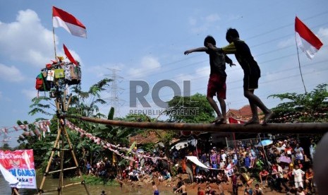 Peserta lomba berusaha meniti batang pohon pinang dalam rangka memeriahkan HUT ke-68 RI di atas Sungai Kalimalang, Jakarta Timur, Sabtu (17/8). (Republika/Rakhmawaty La'lang)