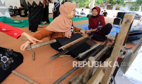 Peserta mencoba alat tenun Gedogan tradisional dalam acara Refleksi Hari Tenun di Gedung kesenian Indramayu, Jawa Barat, Ahad (26/9/2021). Kegiatan yang digelar Tenun Gedogan Fest itu untuk mengenalkan tenun tradisional kepada generasi muda sekaligus sebagai upaya melestarikan tenun Gedogan yang terancam punah. 