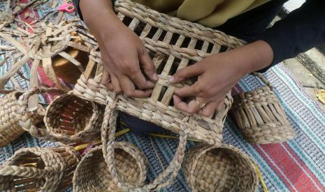 Seorang ibu menganyam batang tanaman enceng gondok kering untuk dijadiakan tas saat pelatihan pembuatan kerajinan. Hasil Kerajinan ini bisa menjadi sumber penghasilan tambahan keluarga yang perlu didukung dengan legaslitas usaha (ilustrasi) 