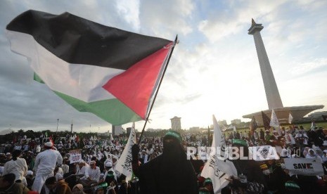 Peserta perempuan aksi solidaritas Palestina mengibarkan bendera dalam aksi solidaritas Palestina di Monumen Nasional, Jakarta, Ahad (17/12). 