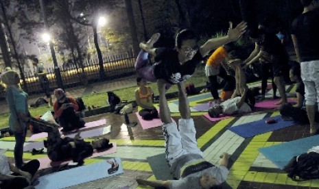 Peserta yoga melakukan teknik Acroyoga saat mengikuti kelas yoga Misbar (gerimis bubar) di pintu IX, Gelora Bung Karno, Jakarta.