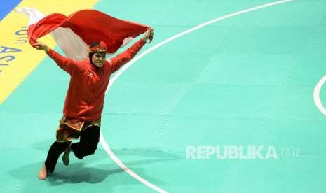 Pesilat Indoensia Puspa Arumsari berlari dengan membawa bendera merah putih usai beraksi pada final cabang pencak silat kelas artistik tunggal putri Asian Games 2018 di Padepokan Pencak Silat TMII, Jakarta, Senin (27/8). Pada pertandingan tersebut Puspa berhasil menyumbangkan medali emas bagi indonesia dengan skor akhir 467.