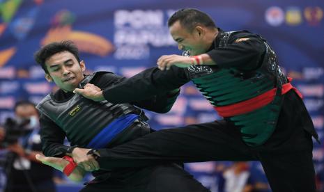 Pesilat putra Bali I Wayan S (kiri) berusaha menjatuhkan pesilat putra Sumatera Barat Anton Yuspermana (kanan) saat bertanding pada penyisihan Pencak Silat kelas H Putra PON Papua di Gor Toware, Kabupaten Jayapura, Papua, Sabtu (9/10/2021)