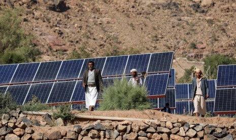 Petani berjalan di tengah panel surya di perkebunan di Wadi Dhahr, dekat Sanaa, Yaman, 28 Oktober 2019. Yaman beralih ke tenaga surya di tengah kekurangan energi akibat perang.