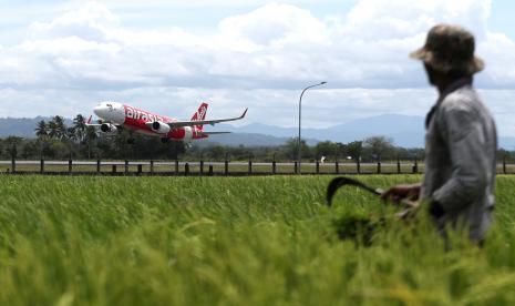 Petani melihat pesawat maskapai penerbangan Air Asia lepas landas dari Bandara Sultan Iskandar Muda. PT Angkasa Pura II Cabang Bandara Internasional Sultan Iskandar Muda menyalurkan program Pendanaan Usaha Mikro Kecil (PUMK) tahap IV Rp 1 miliar.