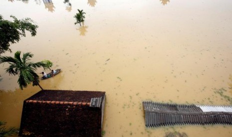 Petani mengayuh sampan di tengah desa yang banjir di Hanoi, Vietnam, Jumat (13/10).