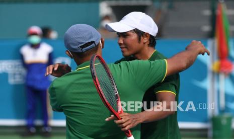 Petenis Jawa Timur M Fifqi Fitriadi (kanan) berpelukan dengan pelatihnya usai mengalahkan petenis Bengkulu Aditya Hari Sasongko dalam babak final tenis beregu putra PON Papua di Jayapura, Papua, Ahad (3/10/2021). M Rifqi berhasil menang sekaligus memastikan emas bagi Jawa Timur dengan skor 2-0. 