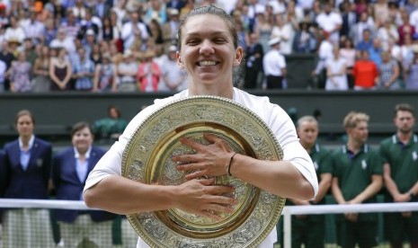 Petenis Rumania, Simona Halep memeluk trofi Wimbledon setelah mengalahkan Serena Williams pada laga final, Sabtu (13/7).