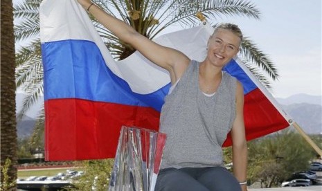 Petenis Rusia, Maria Sharapova, berpose bersama trofi dan bendera Rusia usai mengalahkan petenis Denmark, Caroline Wozniacki, di final tunggal putri turnmanen BNP Paribas Terbuka di Indian Wells, California, Ahad (17/3).