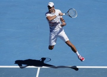 Petenis Serbia, Novak Djokovic, melepaskan pukulan forehand saat menghadapi petenis Kolombia, Santiago Giraldo, di putaran kedua turnamen Australia Terbuka di Melbourne, Australia, Kamis (19/1). 