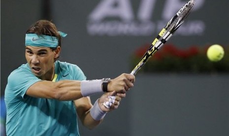 Petenis Spanyol, Rafael Nadal, melepaskan pukulan kerasnya saat menghadapi petenis Amerika Serikat, Ryan Harrison, di turnamen BNP Paribas Terbuka di Indian Wells, California, Sabtu (9/3).  