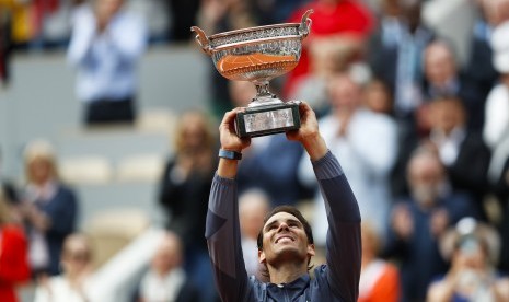 Petenis Spanyol Rafael Nadal mengangkat trofi saat merayakan 12 kali kemenangannya di Prancis Terbuka setelah menaklukkan petenis asal Austria Dominic Thiem dalam empat set pertandingan di stadion Roland Garros, Paris, Ahad.