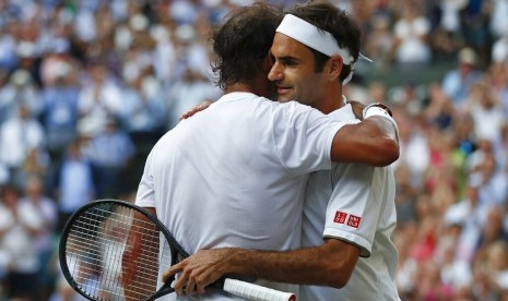 Petenis Swis Roger Federer (kanan) dan Rafael Nadal berpelukan usai pertandingan semifinal Wimbledon di London, Jumat (12/7) waktu setempat. Federer melaju ke final dan bertemu Novak Djokovic.