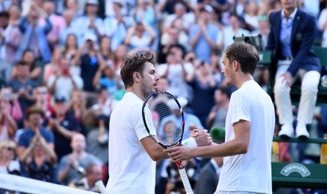 Petenis Swiss, Stan Wawrinka (kiri) bersalaman dengan petenis asal Rusia, Daniil Medvedev seusai laga putaran pertama Wimbledon, Senin (3/7). Wawrinka kalah engan skor 4-6, 6-3, 4-6, 1-6. 