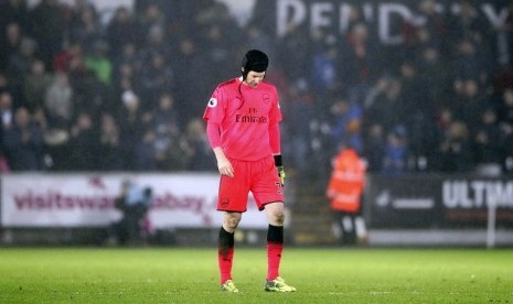 Petr Cech berjalan tertunduk seusai membuat kesalahan yang membuat Arsenal kalah 1-3 dari Swansea City, Rabu (31/1) dini hari WIB.