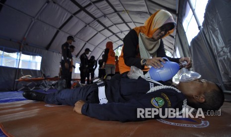 Petugas Badan Nasional Penanggulangan Bencana (BNPB) melakukan evakuasi korban bencana saat glasi bersih simulasi penanganan bencana gempa di Halaman Gedung Sate, Jalan Diponegoro, Kota Bandung, Senin (24/4).