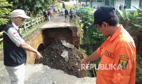 Petugas Badan Penanggulangan Bencana Daerah (BPBD) Kabupaten Sukabumi meninjau jembatan yang ambruk di perbatasan antara Kecamatan Parungkuda dan Ciambar, Kabupaten Sukabumi, Selasa (24/1).