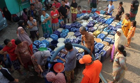 Petugas Badan Penanggulangan Bencana Daerah (BPBD) memberikan bantuan air bersih kepada warga yang dilanda kekeringan. 