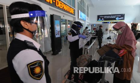 Petugas bandara memakai masker dan pelindung wajah saat mengecek dokumen milik penumpang pesawat di Bandara Adi Soemarmo, Boyolali, Jawa Tengah, Jumat (12/6/2020). Bandara Adi Soemarmo menerapkan adaptasi normal baru baik petugas bandara dan para penumpang pesawat komersial dengan menggunakan masker, pelindung wajah, sarung tangan, tempat cuci tangan, cairan antiseptik dan berjaga jarak guna pencegahan penyebaran COVID-19.