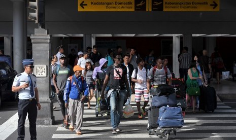 Petugas bandara mengawasi penumpang yang baru tiba di terminal kedatangan domestik Bandara Ngurah Rai, Denpasar, Jumat (24/6).