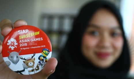 Petugas bandara menunjukkan pin dukungan terhadap pelaksanaan pesta olahraga Asian Games 2018 seusai Deklarasi Komitmen Dukungan Penyelenggaraan Asian Games 2018 Komunitas Bandara Soekarno Hatta (KOMBATTA) di kawasan bandara Soekarno Hatta, Tangerang, Banten, Kamis (12/7). 