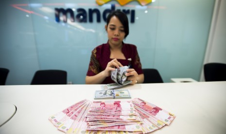 Petugas Bank Mandiri menghitung pecahan uang rupiah dan dollar Amerika Serikat di Jakarta, Jumat (18/3).