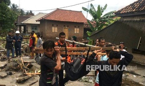 Petugas Basarnas dibantu warga mengevakuasi korban meninggal akibat tsunami di pesisir Cinangka, Serang, Banten, Ahad (23/12). 