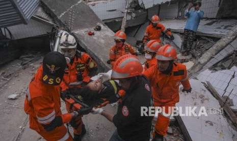 Petugas Basarnas membawa korban selamat gempa dan tsunami yang terjebak di dalam restoran Dunia Baru, Palu, Sulawesi Tengah, Minggu (30/9).